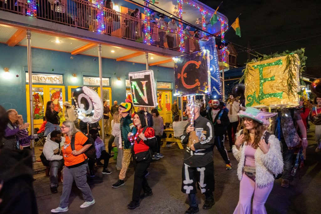Puppeteer anti-floats wearing signs spelling our O-N-C-E lead the Les Fous du Carnaval parade in revelry. 